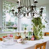 Wrought iron chandelier above white, set table in window bay