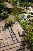 Wooden deck and paved terrace next to lily pond