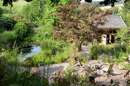 Seating area in garden and holiday cottage in rural surroundings with small pond