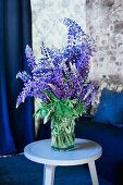 Blue and purple flowering lupins in preserving jar on pastel blue side table