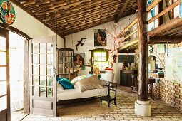 Bed between French windows in rustic bedroom with roof support and gallery structure; pictures of sea goddess Lemanja