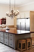 Nostalgic, country-house kitchen with large, stainless steel appliance fronts and wrought iron chandelier