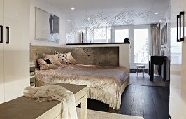 Luxuriöser Schlafbereich in offenem Wohnraum hinter halbhoher Trennwand; hinter der Trennwand das Badezimmer