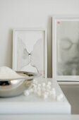 Arrangement of artworks in white picture frames leaning on white wall