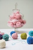 Balls of wool of various colours on table & in glass jar