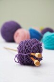 Several balls of wool with knitting needles through one ball