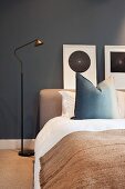 Simple bedroom with dark walls, bed, standard lamp & pictures on wall