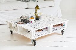 DIY coffee table made from euro pallets on castors and couch on white wooden floor