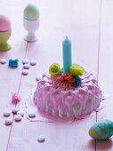 Miniature cake decorated with pink icing, candle & paper flowers