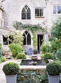 Planted courtyard of Gothic country house with box bushes around fountain