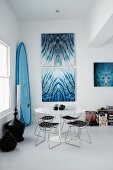 Klassiker Drahtgestell Stühle an rundem Tulip Table im Esszimmer, Bilder mit Wassermotiv an Wand und Surfbrett
