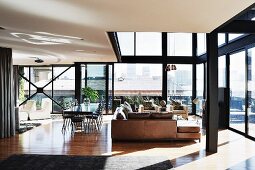 Penthouse apartment with steel and glass facade, comfortable lounge area with leather sofa and dining area
