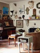 Decorative collector's items and pictures on living room wall above antique piano and vintage-style couch, coffee table and side table