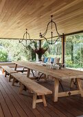 Dining room with rustic table, benches and glass walls with view of garden
