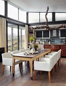 Offener, lichtdurchfluteter Wohnraum mit Küchenzeile im Stilmix und rustikalem Esstisch mit eleganten Armstühlen