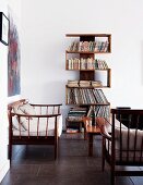 Eigenwillig verwinkeltes Bücherregal an weisser Wand in klarem, hellen Wohnzimmer mit filigranen Holzmöbeln