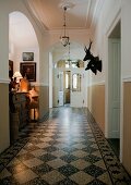 Pale hallway in manor house with traditional, black and white marble floor and hunting trophies on wall
