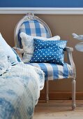 Antique chair covered in blue and white checked fabric with polka dot scatter cushion against beige wall