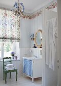 Romantic bathroom with floral wallpaper frieze in nostalgic country-house style and oval, gilt-framed mirror