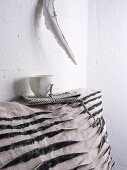 White cup on top of grey and black scatter cushion
