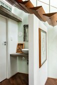 Schwebende Treppenstufen aus dreieckigen Holzprofilen und freistehende Trennwand vor einem Waschtisch