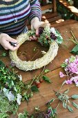 Decorating straw wreath with flowers and blackberries