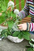 Woman's hands arranging garlic flowers in small basket