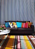 Mixture of patterns - striped rug and wall hanging, dark grey sofa and colourful scatter cushions