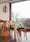 Solid wooden table and old bentwood chairs in dining area with floor-to-ceiling window