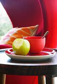 Roter Teller mit angebissenem Apfel und Schale auf Beistelltisch