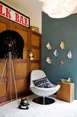 Vintage-style seating area with standard lamp, shell easy chair & books inverted on hand-made wall brackets