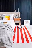 Bedroom with red and white striped carpet runner in front of black wooden paneling