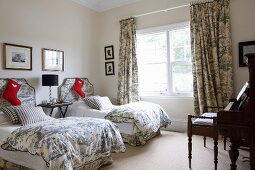 Santa Claus boots on single beds with Toile De Jouy bed linen and curtains in the guest bedroom