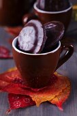 Autumn leaves used as coaster for espresso cup filled with biscuits