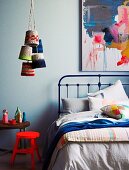 Neon-red stool, retro metal bed and bunch of pendant lamps with dip-dyed knitted lampshades hanging from ceiling