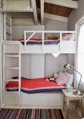Hand-crafted bunk bed with ladder and retro, stainless steel table lamp on bedside table in wood-clad room