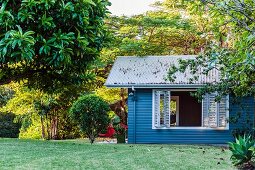 Wooden play house painted blue in well-tended garden