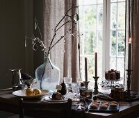 Glass decorations hanging on branches in demijohn on festively set table
