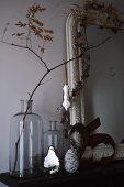 Christmas decoration hanging from branch in a large glass jar next to antique frame