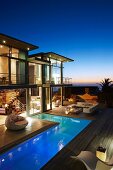 Luxury house with L-shaped floor and illuminated terrace in fabulous twilight setting with sea view