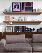 Collection of artworks, ceramic vases and bowls on sideboard behind comfortable designer sofa