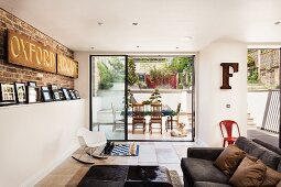 Englische Designerwohnung mit aufgestellter Fotogalerie und Sichtmauerwerk im Wohnbereich mit Terrassenblick