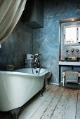 Narrow vintage bathroom with free-standing bathtub, rustic wooden floor and grey-blue marbled paint effect on walls
