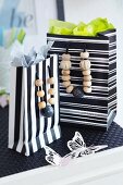 Black and white striped gift bags with wooden beads threaded onto handles on black table mat