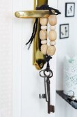 Key lanyard decorated with wooden beads hanging on brass door handle