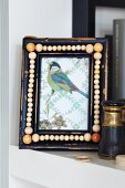 Picture of bird in frame decorated with wooden beads