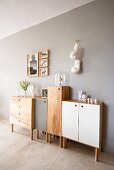 Half-height, wooden console cabinets, some with coloured doors, against wall painted pale grey