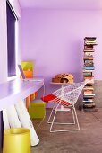 Lila getönter Raum mit geschwungener Platte an Wand in gleichem Farbton und Klassiker Stuhl aus weißem Metallgitter