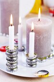 Verschiedene brennende Kerzen auf gestapelten oder aneinander gereihte Kronkorken arrangiert