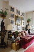 Gilt-framed, historical paintings above red velvet sofa flanked by antique tray supports with pots of lavender